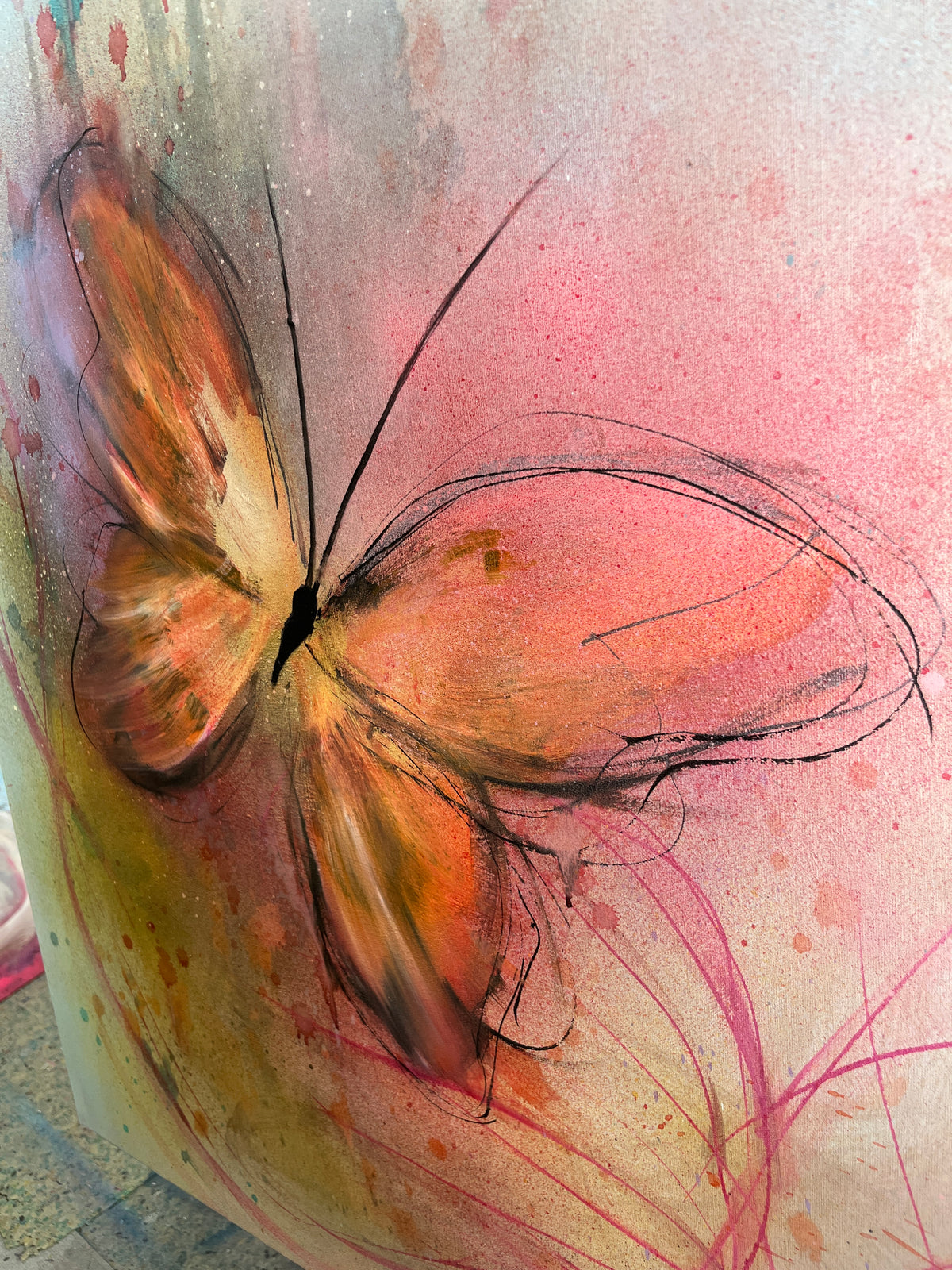 Abstract butterfly artwork painted on a textured surface, featuring orange, pink, black, and yellow tones with expressive brushstrokes and splatter details.
